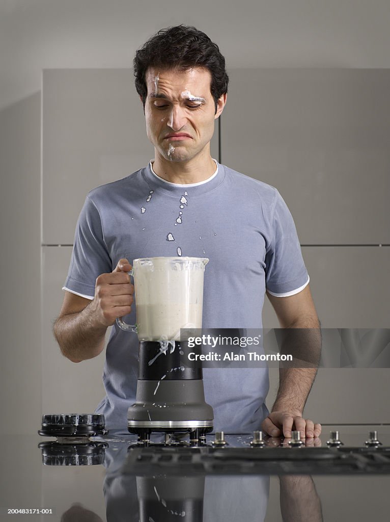 Man splashed by smoothie from blender in kitchen