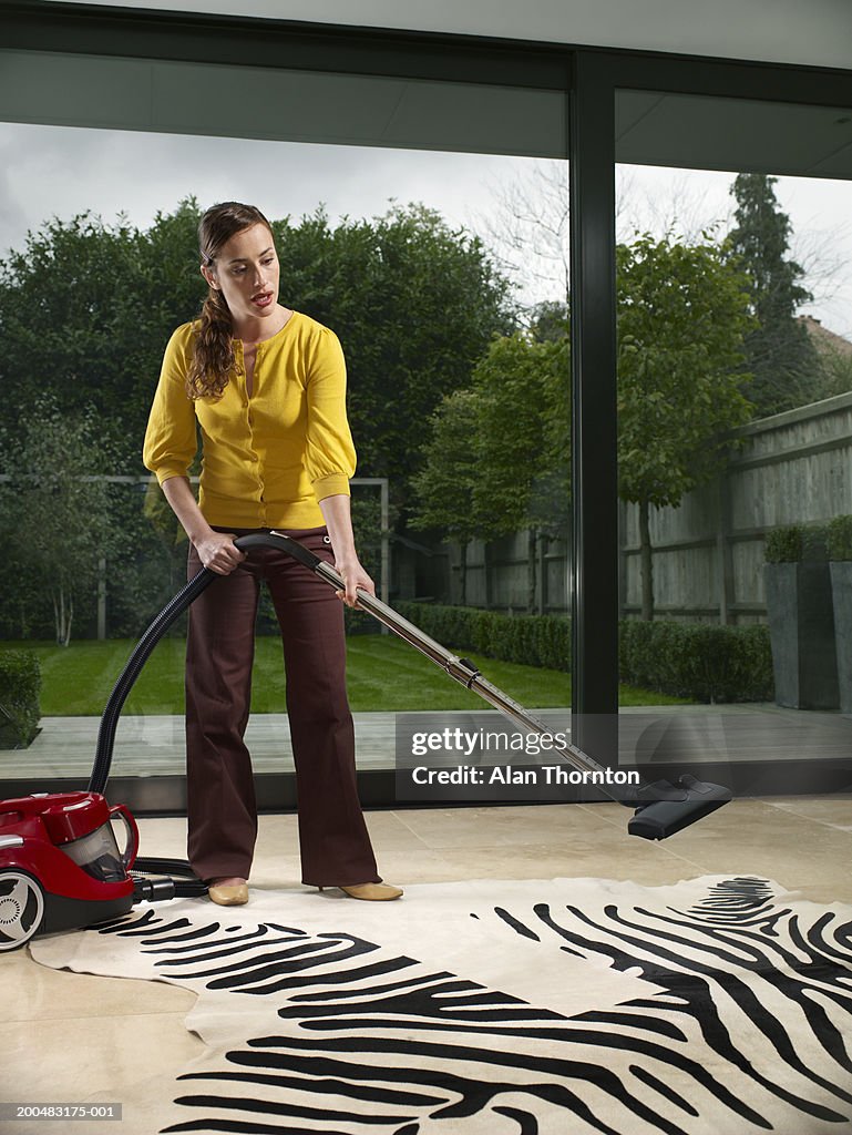 Woman sucking up rugs stripes with vacuum cleaner