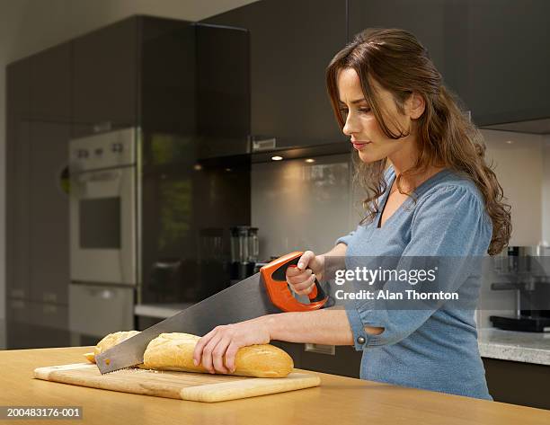 woman cutting bread with saw in kitchen - woman bread stock pictures, royalty-free photos & images