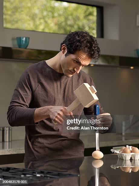 man cracking egg with mallet and chisel in kitchen - out of context ストックフォトと画像