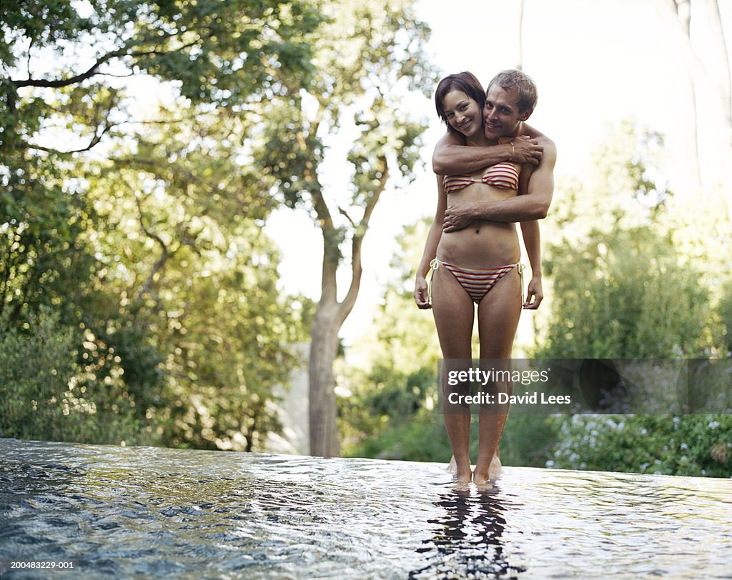 Young couple in swimwear embracing in shallow water