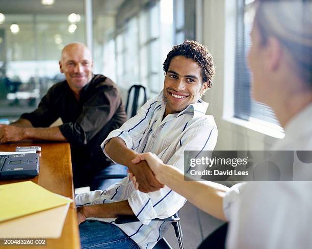 businessman and businesswoman shaking hands at conference table - congratulating imagens e fotografias de stock