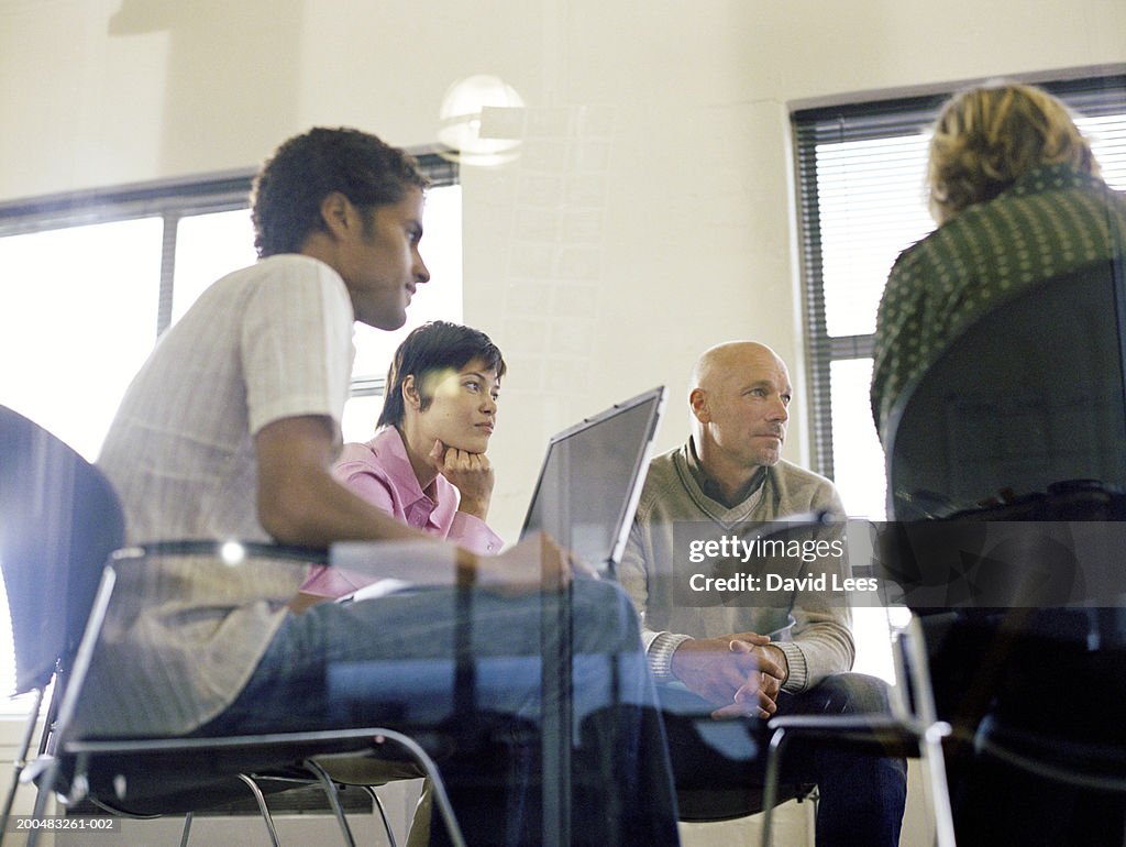 Business people having meeting in office, view through glass, low angle view