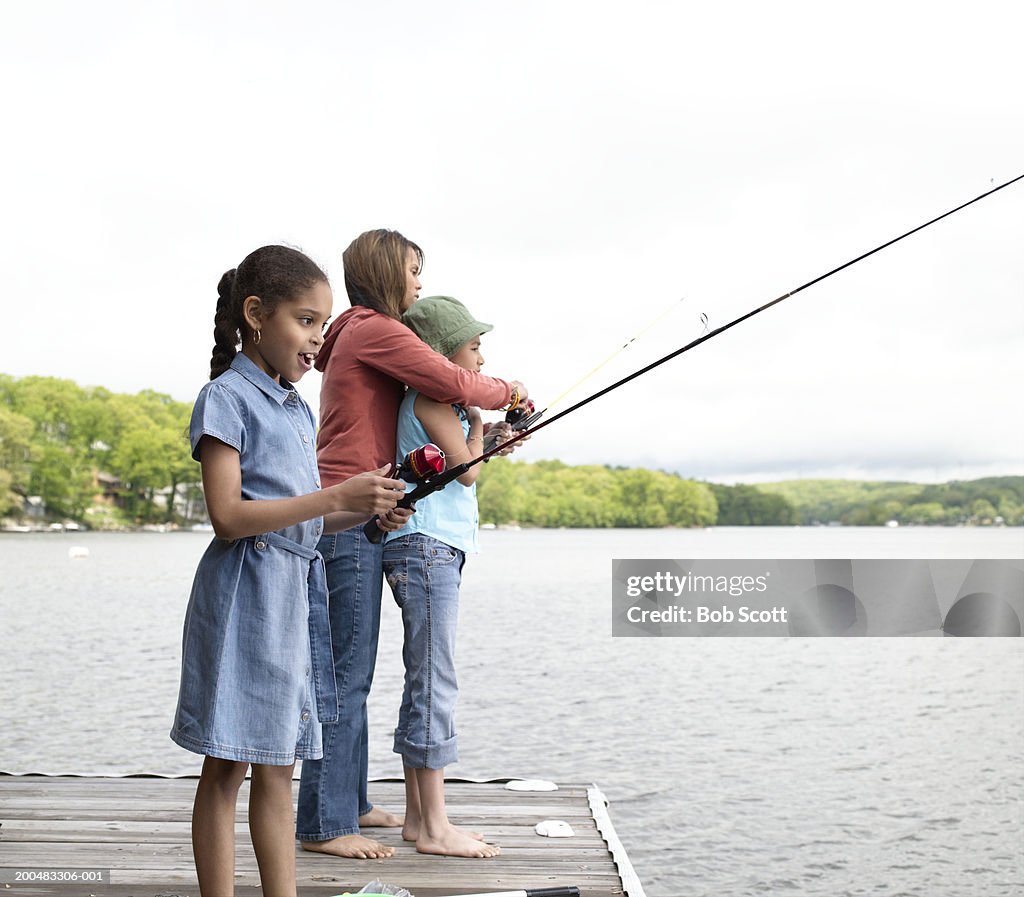 Mother and daughters (8-10) fishing, side view