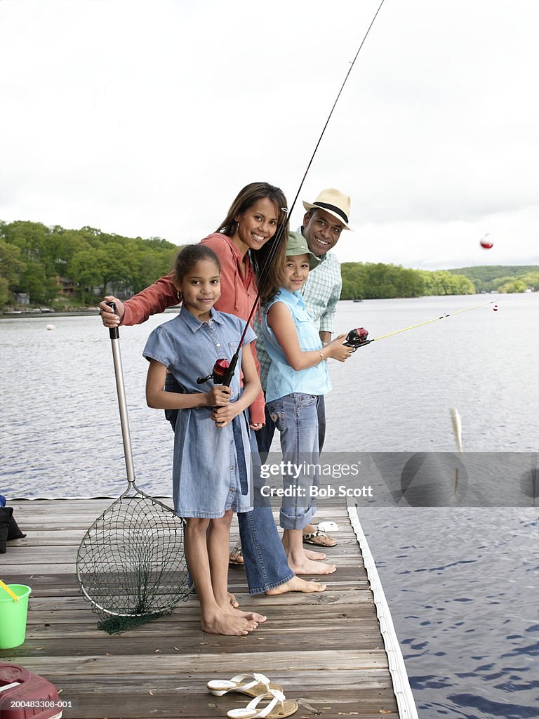 Parents and daughters (8-10) fishing, girl with fish on line