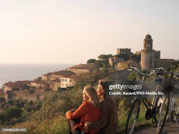 italy, tuscany, couple with bicycles looking at sea, sunrise - tuscany stock pictures, royalty-free photos & images