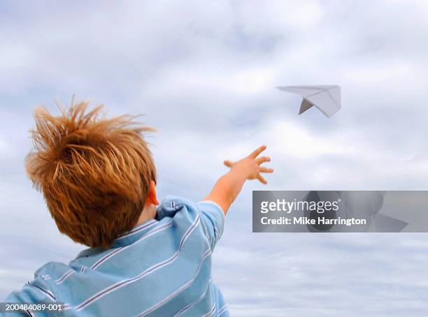 boy (4-6) throwing paper aeroplane, outdoors, rear view - throwing foto e immagini stock