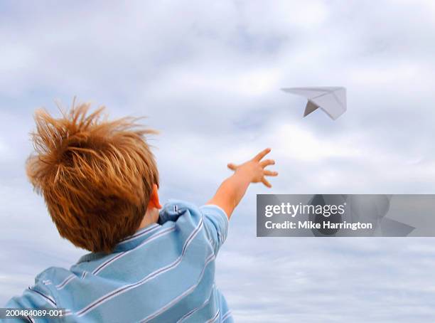 boy (4-6) throwing paper aeroplane, outdoors, rear view - arremessar imagens e fotografias de stock