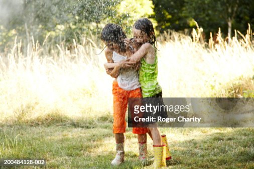 Two Girls With Wet Clothes Hugging And Laughing Under Sprinkler High ...