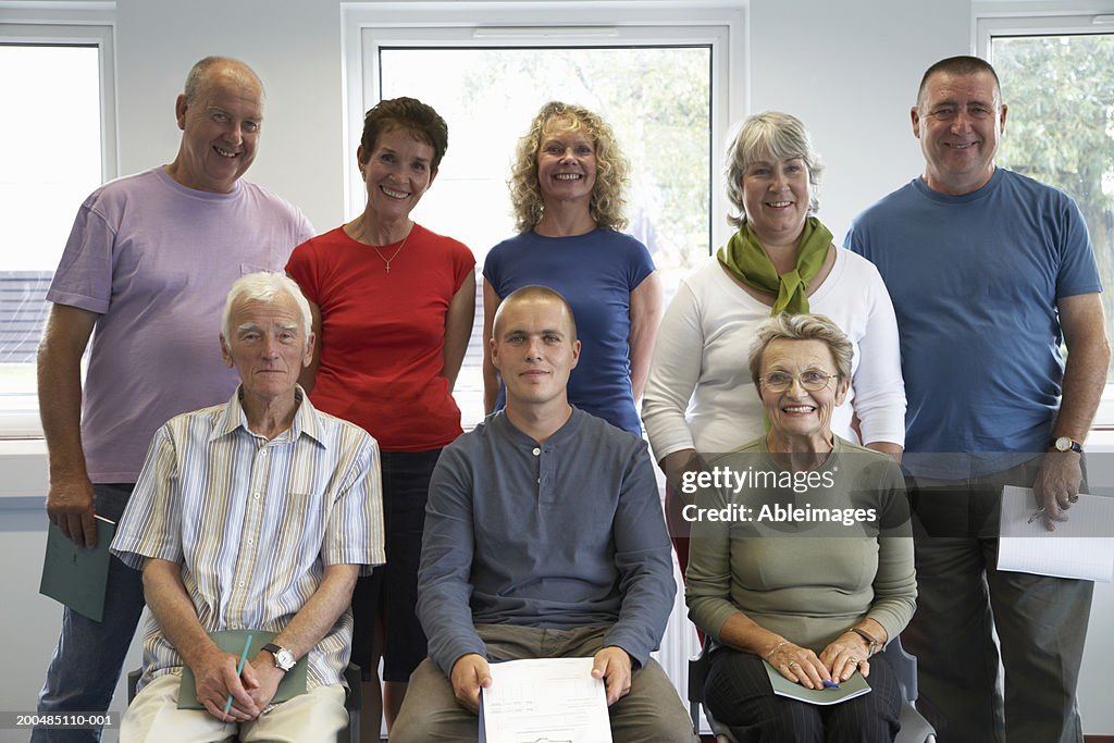 Group of people standing in adult education class, smiling, portrait