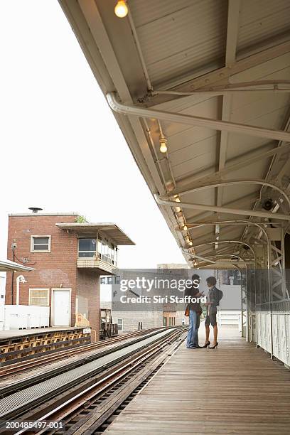 young couple talking to each other on train platform - bright chicago city lights stock pictures, royalty-free photos & images