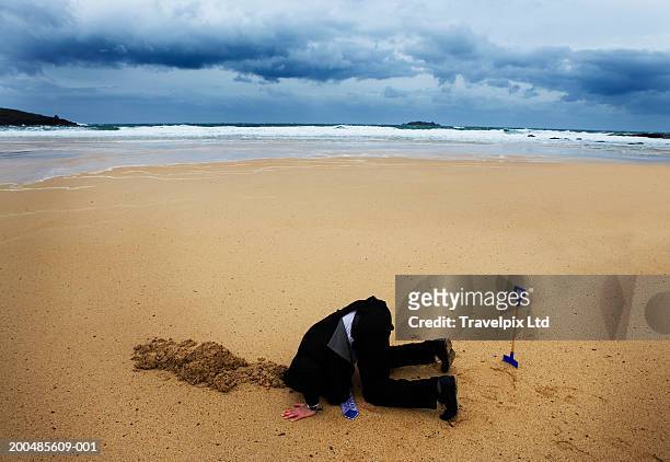 businessman with head in sand, elevated view - digging beach photos et images de collection