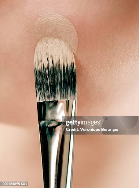 young woman applying foundation with make-up brush, close-up - pennello-da-trucco foto e immagini stock