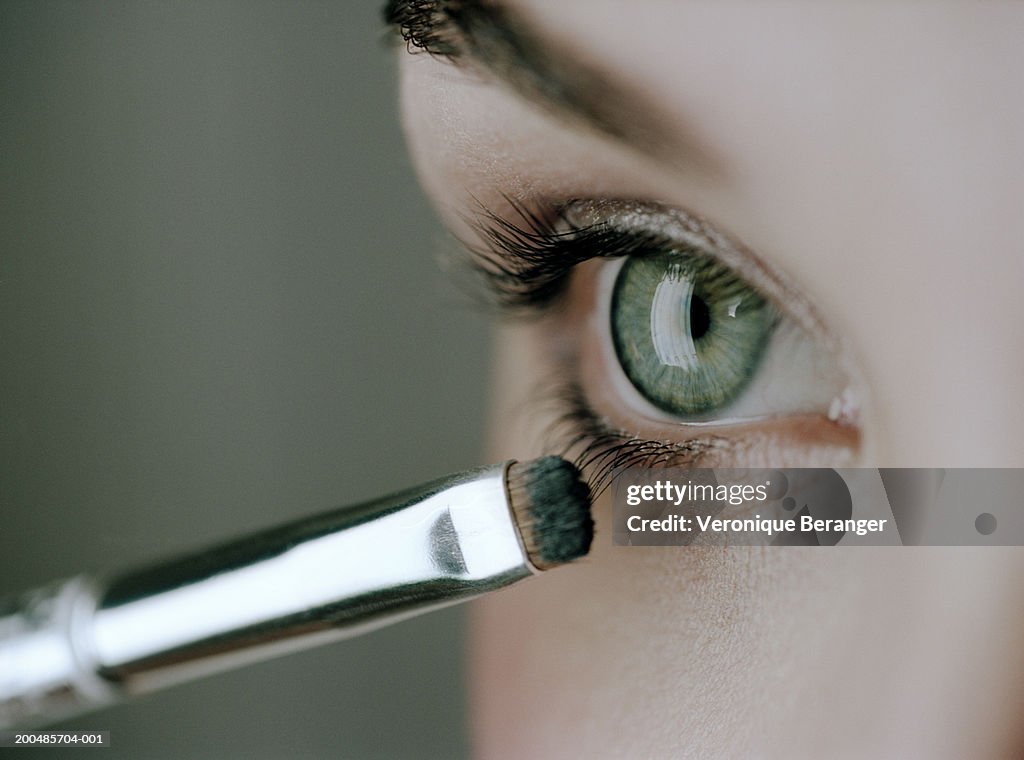 Young woman applying mascara, close-up of eye and eyelashes