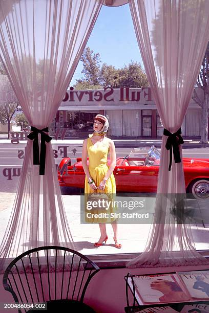 woman in vintage clothes standing outside beauty salon - vintage handbag stock pictures, royalty-free photos & images