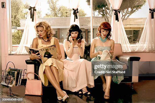 women in vintage clothing waiting inside beauty salon - reading magazine stock-fotos und bilder