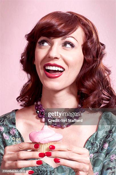 woman in vintage dress holding cupcake - woman holding cake stock-fotos und bilder