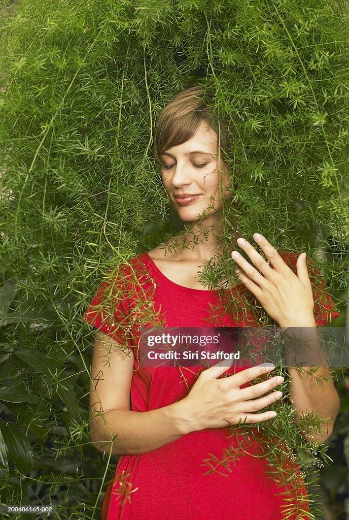 Woman holding on plant in greenhouse