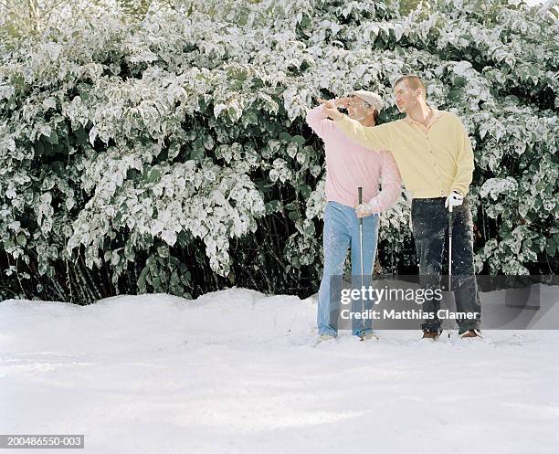 two men with golf clubs in snow looking to side - fehl am platz stock-fotos und bilder