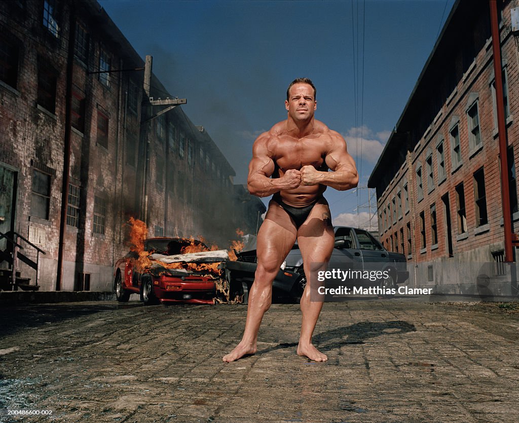 Bodybuilder flexing, car collision in background