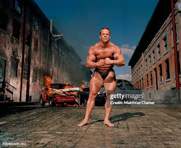 bodybuilder flexing, car collision in background - flexing muscles foto e immagini stock