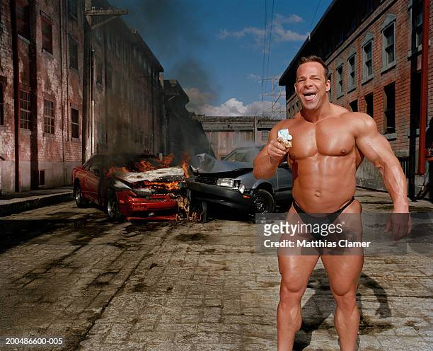 bodybuilder eating ice cream cone, car collision in background - accidents and disasters stock-fotos und bilder