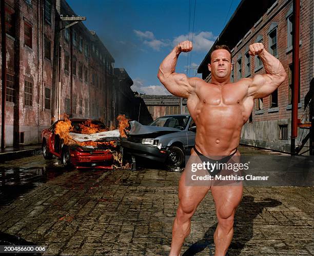 bodybuilder flexing, car collision in background - bodybuilder fotografías e imágenes de stock