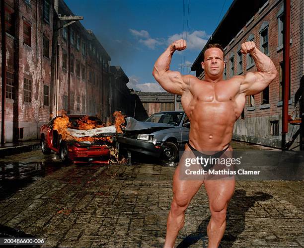bodybuilder flexing, car collision in background - mascolinità foto e immagini stock