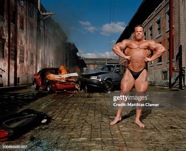 bodybuilder flexing, car collision in background - body building photos et images de collection