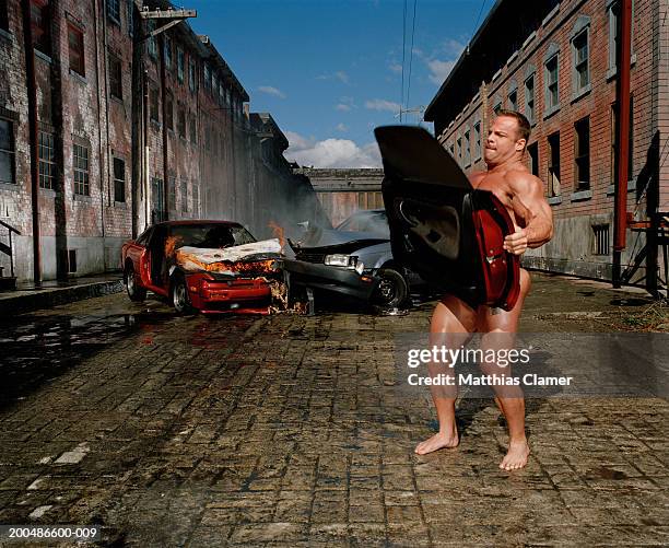 bodybuilder carrying car door, car collision in background - body building stockfoto's en -beelden