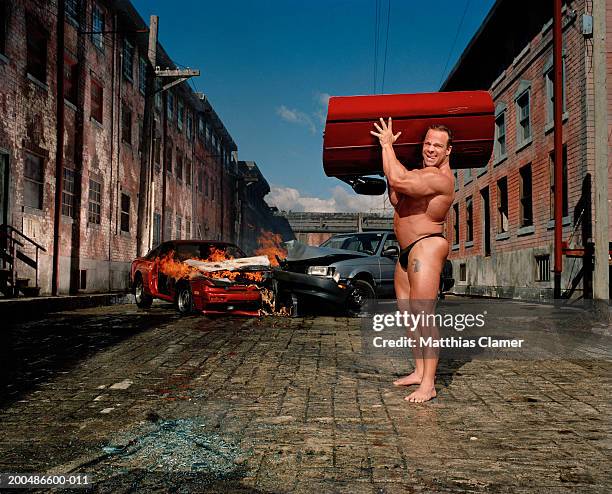 male bodybuilder carrying auto part away after collision - body builder funny stock-fotos und bilder