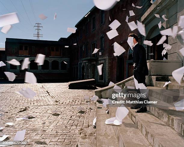 businessman on steps, papers flying in wind (blurred motion) - burocrazia foto e immagini stock