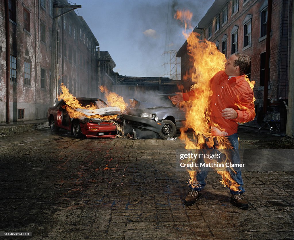 Man on fire, car collision in background