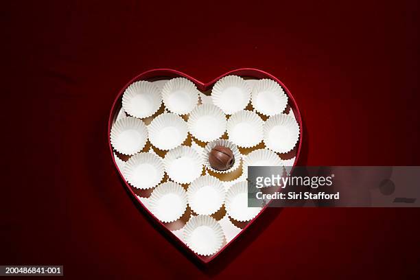 chocolate bon-bon and empty wrappers in heart shaped box - chocolate box stockfoto's en -beelden