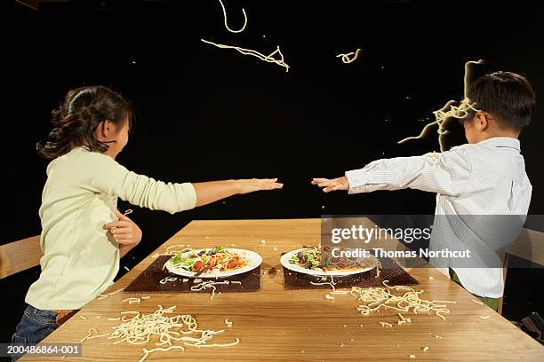 brother and sister (4-10) throwing pasta at one another at table - food fight stock pictures, royalty-free photos & images