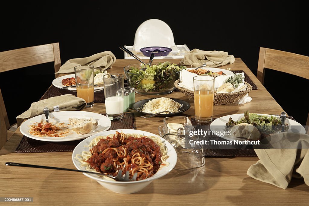 Dining table with plates, pasta, salad and parmesan cheese