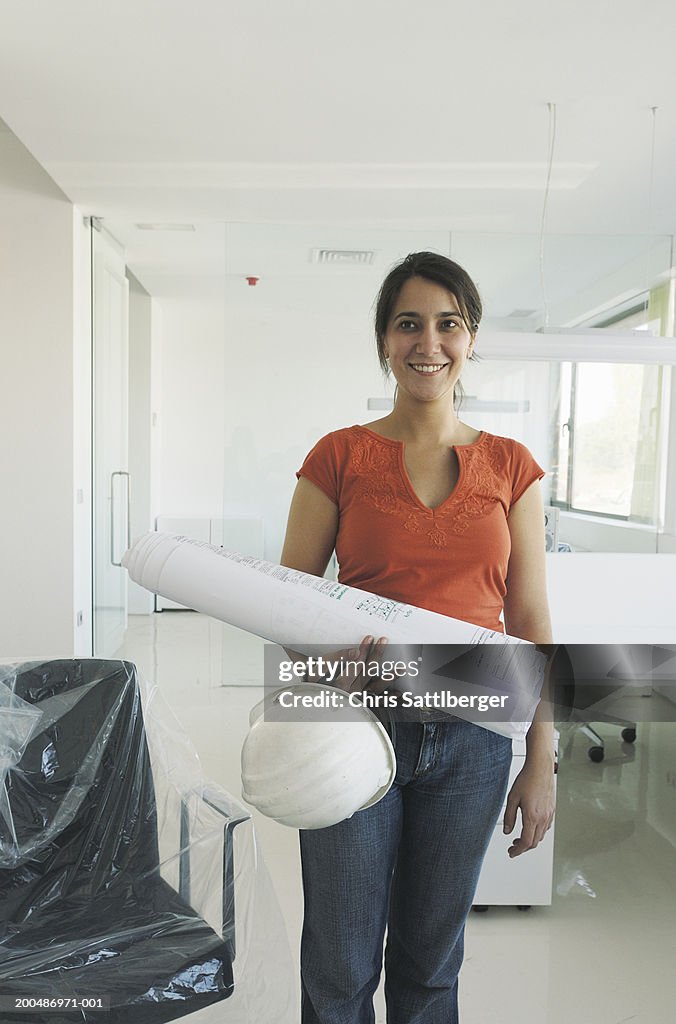 Female architect with plan and hard hat in newly finished office