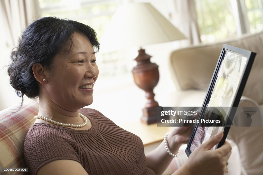 Mature woman sitting at home, looking at photograph