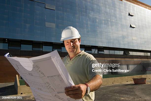 man holding plans on building site, smiling, portrait, close-up - architekt helm plan stock pictures, royalty-free photos & images
