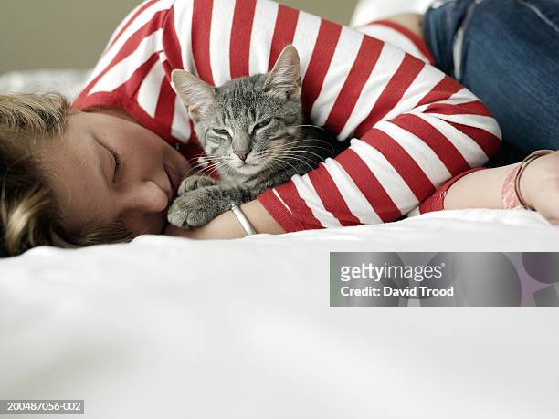 girl (11-13) lying on bed, embracing cat, eyes closed, close-up - cats on the bed stock pictures, royalty-free photos & images