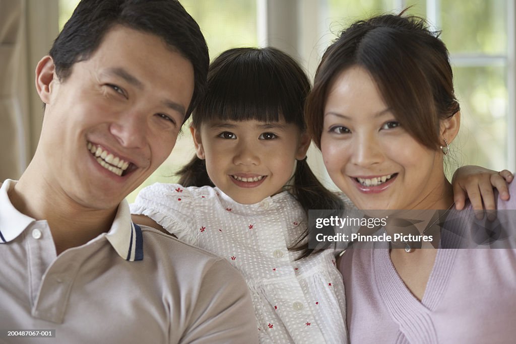 Girl (4-5) smiling with parents, portrait