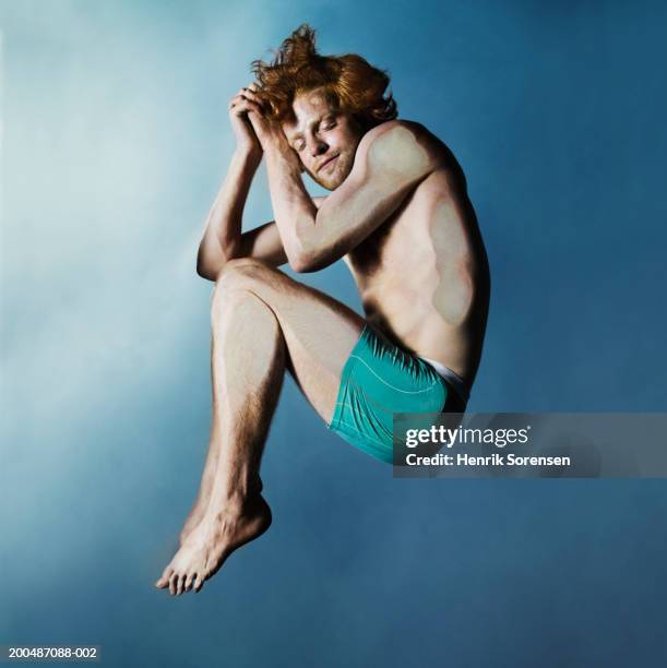 young man lying asleep on glass pane - hugging knees stock pictures, royalty-free photos & images