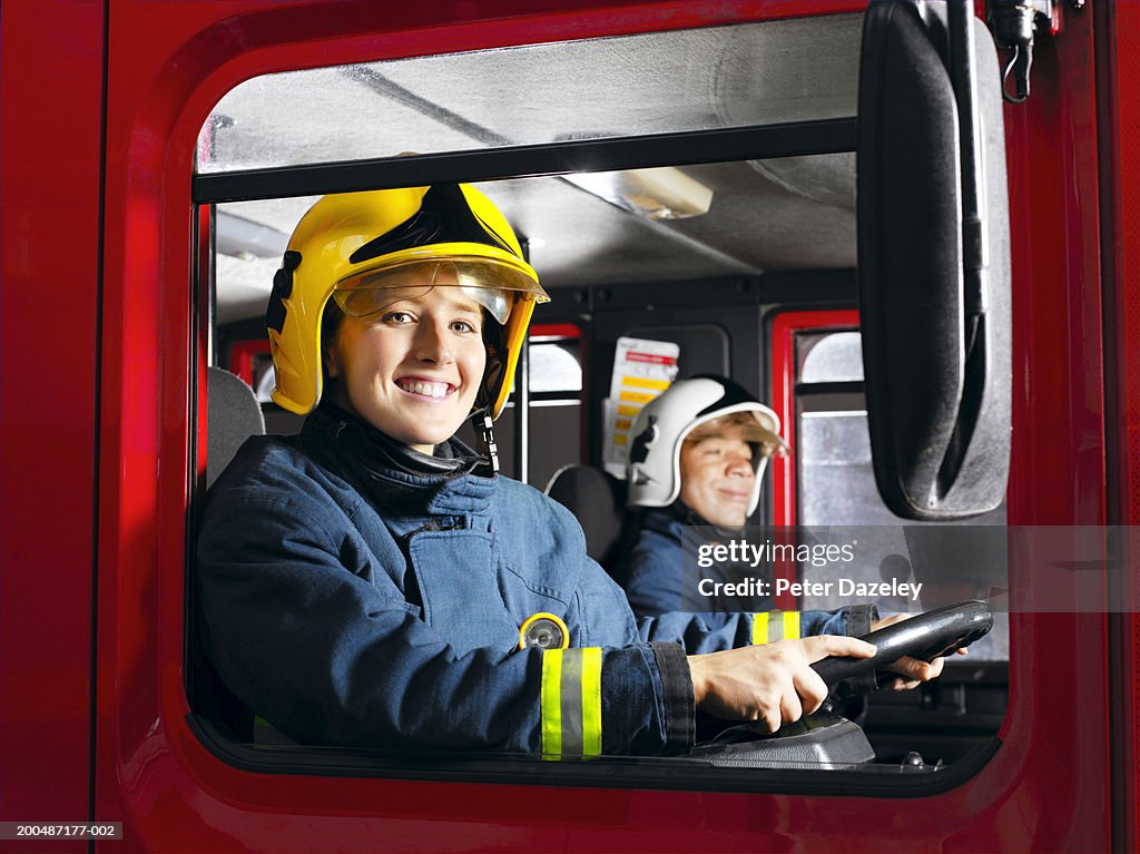 Woman driving firetruck, smiling, portrait