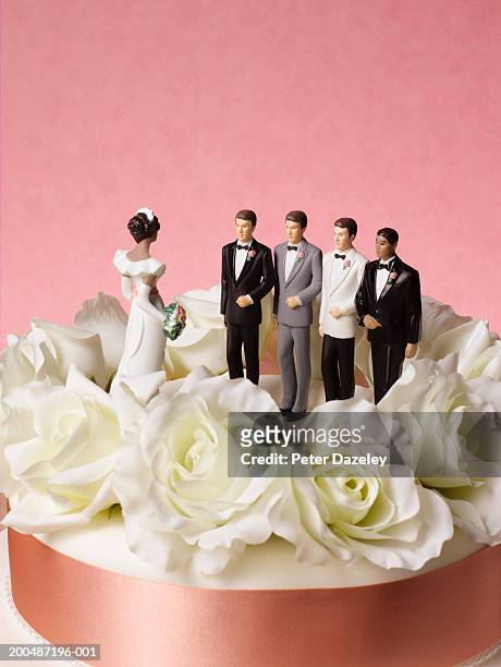 bride figure on wedding cake with a choice of four grooms - polygamie stockfoto's en -beelden