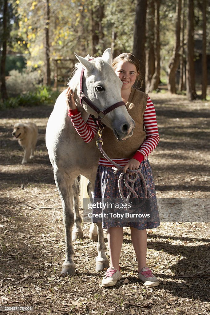 Girl (11-13) embracing horse, smiling, portrait