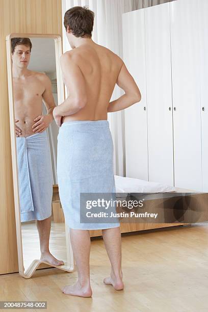 young man dressed in towel, standing in front of mirror - corpo normale foto e immagini stock