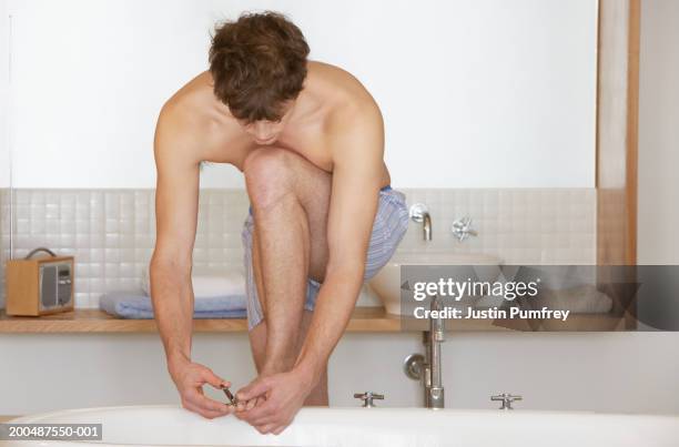 young man leaning on bath cutting toenails - toenail stock pictures, royalty-free photos & images