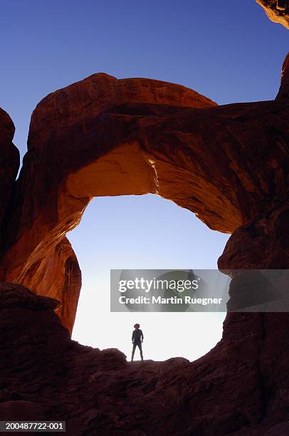 silhouette of man standing below natural arch - double arch stock pictures, royalty-free photos & images