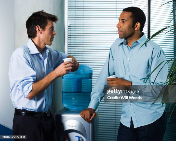 two businessmen by water machine - water cooler stock pictures, royalty-free photos & images