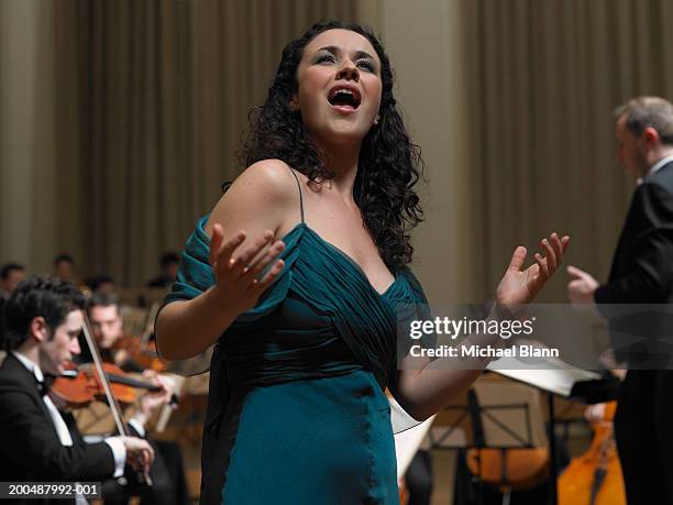 female singer performing with orchestra - muziekstandaard stockfoto's en -beelden